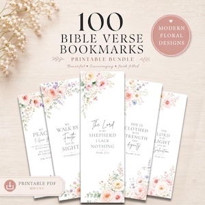 May include: A set of five vertical bookmarks featuring floral illustrations in shades of pink, peach, and lavender. Each bookmark displays a unique Bible verse in black serif and script typography. The text includes 100 BIBLE VERSE BOOKMARKS.