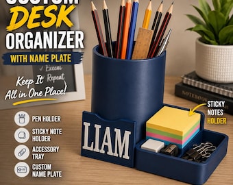 May include: A dark blue desk organizer featuring a cylindrical pen holder, a rectangular tray for sticky notes, and a front name plate displaying the name LIAM in white letters. The organizer holds various pencils, a ruler, and metal clips.