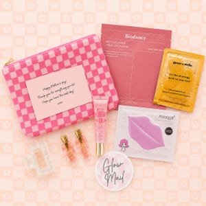 Op de afbeelding: Een verzameling schoonheidsproducten, waaronder een roze en witte geruite cosmetische tas met een handgeschreven Moederdagkaart. Andere items zijn gezichtsmaskers, oogmaskers, lipmasker, rozenbottelolie en haarclips.
