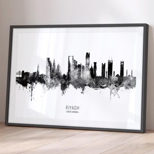 Op de afbeelding: Zwart-witte aquarel stadsgezicht van Riyad, Saoedi-Arabië. De skyline toont hoge gebouwen en een brug. De naam van de stad en het land staan ​​onder de skyline.
