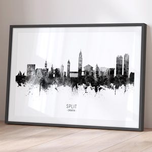 May include: Black and white watercolour cityscape print of Split, Croatia. The print features a skyline of buildings with a church steeple and a tall tower. The print is framed in a black frame.