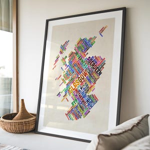 a large framed poster with a colorful, abstract design of various words and phrases arranged in a map-like shape, representing different cities or regions.