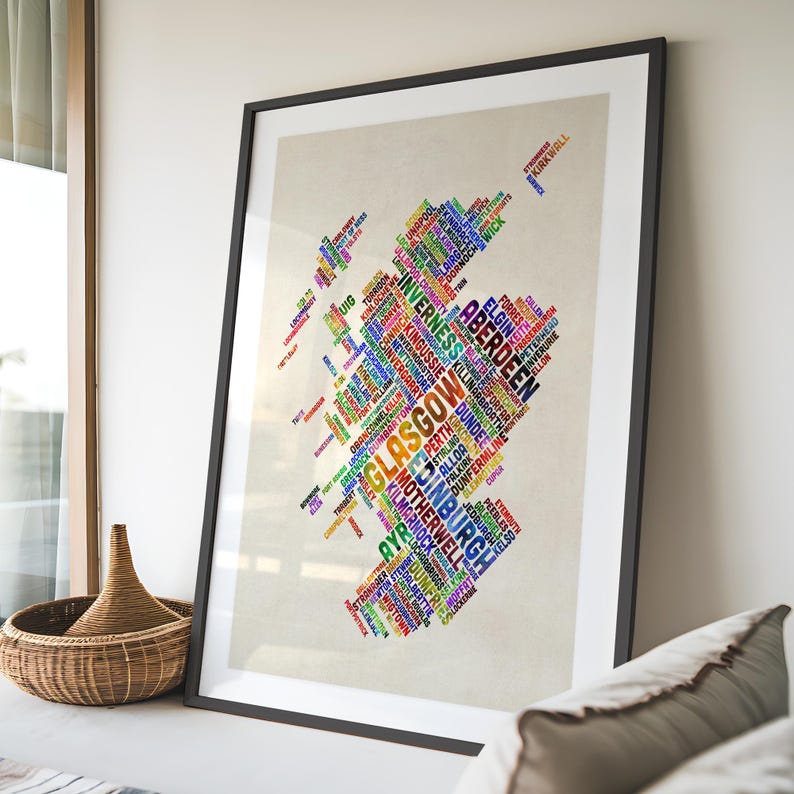a large framed poster with a colorful, abstract design of various words and phrases arranged in a map-like shape, representing different cities or regions.