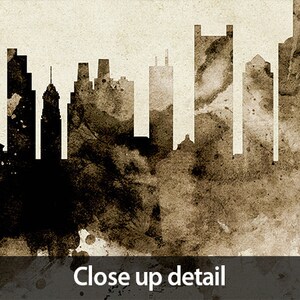 May include: A black and white silhouette of a city skyline with a brown watercolor background. The skyline features tall buildings and a church steeple.