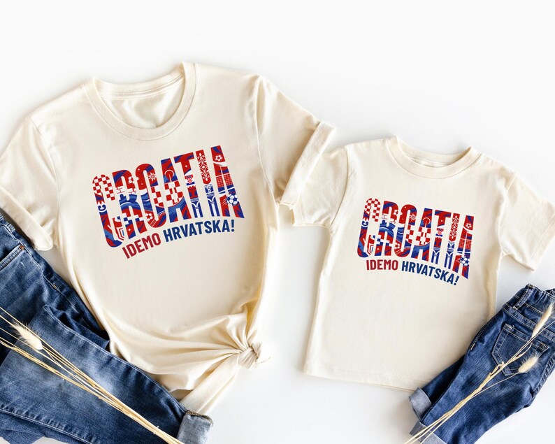 two white t-shirts with the word "Croatia" printed on them, along with a smaller child's t-shirt. The t-shirts are laid out on a white background, and there are also some jeans visible in the image.