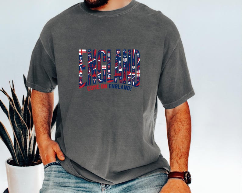 A man wearing a grey t-shirt with the word "ENGLAND" printed on it, along with various symbols and text related to the United Kingdom.