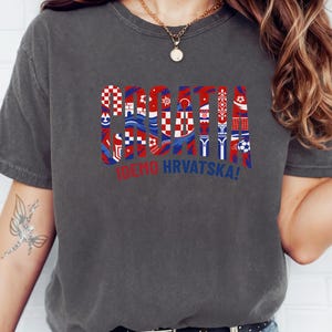 A person wearing a gray t-shirt with a graphic design featuring the flag of Croatia and the text "IWEND HRVATSKA!"