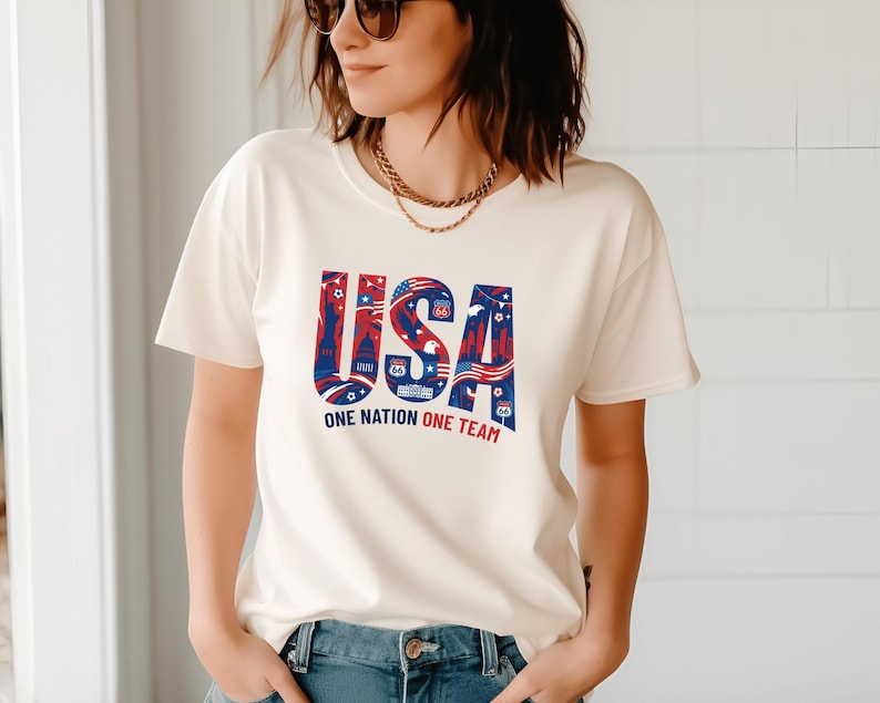 A woman wearing a white t-shirt with the text "USA" and "ONE NATION ONE TEAM" printed on it.