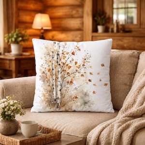 Peut inclure: Un coussin carré décoré d'une illustration à l'aquarelle représentant des bouleaux à l'écorce blanche et aux feuilles d'automne dorées et brunes. Le motif présente des branches délicates et des feuilles éparpillées sur un fond blanc.