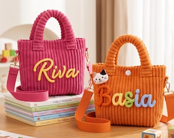 May include: Two corduroy tote bags with detachable shoulder straps. The magenta bag features the name Riva in yellow script. The orange bag features a small cat face patch and the name Basia in multi-coloured, raised, rounded letters.