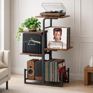 May include: A multi-tiered, black metal and wood record storage unit. The top shelf holds a record player. Other shelves display vinyl records, speakers, and a potted plant. Album covers include "David Bowie" and "Pearl Jam".