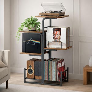 May include: A multi-tiered, black metal and wood record player stand with a turntable on top. The stand holds vinyl records, speakers, and a potted plant. The stand is in a living room setting.