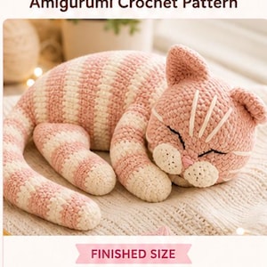 Può includere: Un modello amigurumi di gatto che dorme all'uncinetto. Il gatto è rosa e bianco, con un corpo a strisce e una faccia addormentata. La dimensione finita è di 25-30 cm di lunghezza e 7.6-10 cm di altezza. Il testo "Sleeping Cat" e "Amigurumi Crochet Pattern" sono visualizzati.