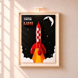 May include: Framed artwork depicting a red and white rocket launching against a black night sky with stars and a crescent moon. The artwork includes the word "TINTIN" and a row of small figures. The rocket has a red fin and a yellow and orange flame.