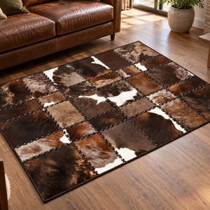Puede incluir: Una alfombra rectangular con un diseño de mosaico compuesto por paneles de piel de vaca en varios tonos de marrón, beige y blanco. Las piezas individuales de piel están cosidas con hilo oscuro visible, creando un patrón de cuadrícula.