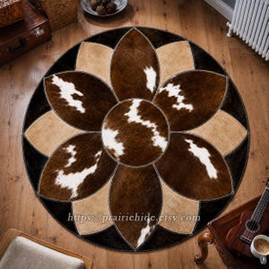 May include: A circular rug featuring a floral-inspired pattern constructed from stitched panels of cowhide in shades of dark brown, tan, and white. The center is a round patch surrounded by petal-shaped segments with visible stitching throughout.