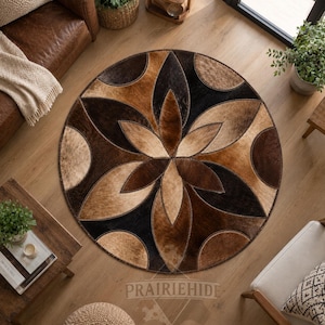 May include: A circular area rug constructed from stitched panels of cowhide in shades of black, dark brown, and tan. The rug features a repeating geometric floral pattern with petal-shaped segments radiating from the center, finished with visible stitching.
