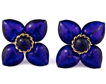 May include: A pair of blue glass flower-shaped earrings with gold accents.