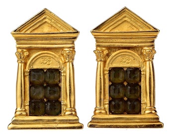 May include: A pair of gold-colored earrings, each shaped like a miniature temple with a triangular pediment and columns. The earrings feature a grid of dark green, square-cut gemstones.