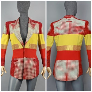 Puede incluir: Una chaqueta roja, amarilla y blanca con un diseño geométrico de lunares y rayas. La chaqueta tiene un cierre de un solo botón.