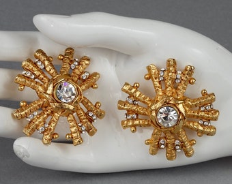 May include: A pair of gold-tone earrings with a starburst design and clear rhinestone accents.