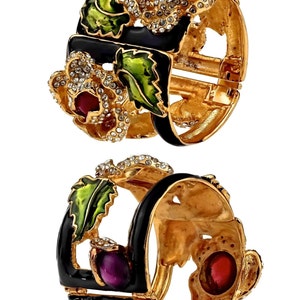 Puede incluir: Un par de pulseras de tono dorado con esmalte negro y detalles de esmalte de colores. Las pulseras est&aacute;n decoradas con diamantes de imitaci&oacute;n y presentan un dise&ntilde;o floral.
