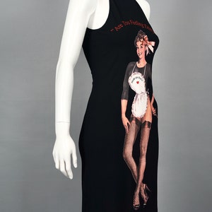 May include: Black halter dress with a graphic of a vintage pin-up girl wearing a white apron that says "Made in Italy." The dress has the text "Are You Feeling Dirty?" in red. The dress is displayed on a mannequin.