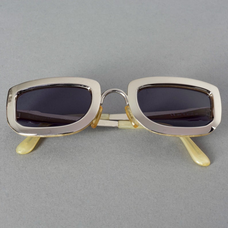 May include: Silver-framed sunglasses with dark lenses and ivory-colored arms.