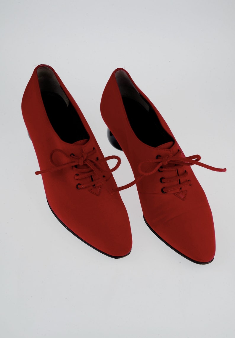 May include: A pair of red lace-up shoes with black laces and a pointed toe. The shoes have a chunky heel.