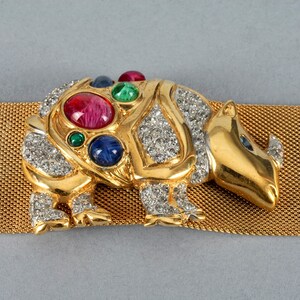 May include: A gold-tone rhinoceros brooch with rhinestones and colorful stones. The brooch is attached to a gold mesh belt.