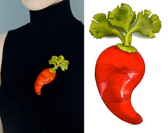 May include: A red and green enamel pin shaped like a radish with green leaves.