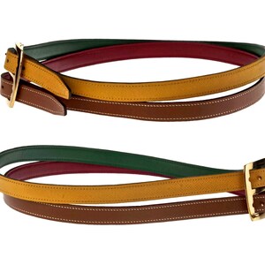 Pode incluir: Um cinto de couro multicolorido com uma fivela dourada. O cinto &eacute; feito de quatro camadas de couro em verde, vermelho, amarelo e marrom.