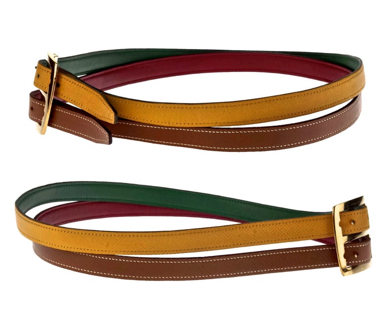 Pode incluir: Um cinto de couro multicolorido com uma fivela dourada. O cinto &eacute; feito de quatro camadas de couro em verde, vermelho, amarelo e marrom.