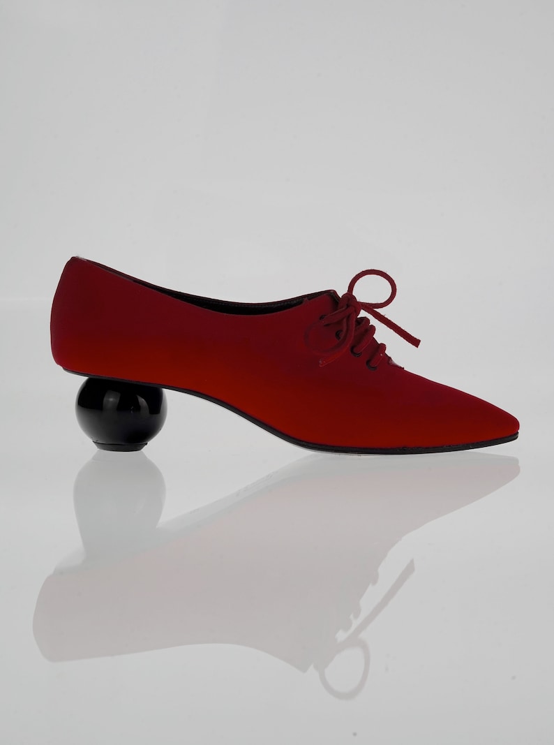 May include: Red satin lace-up shoes with a black ball heel.