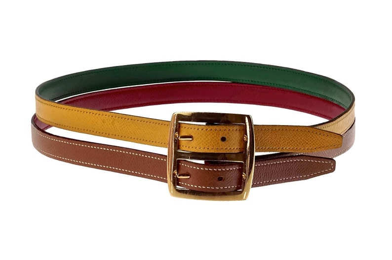 Pode incluir: Um cinto de couro multicolorido com uma fivela dourada. O cinto &eacute; feito de tr&ecirc;s cores diferentes de couro: marrom, amarelo e verde.
