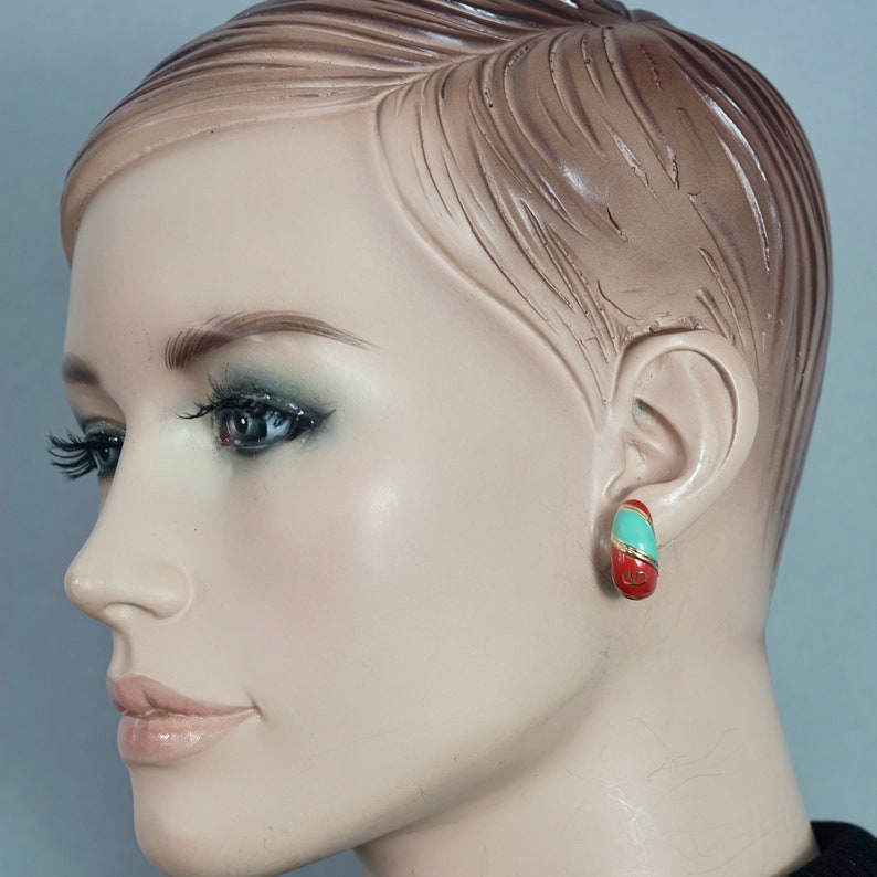 May include: A mannequin wearing a pair of red and turquoise hoop earrings.