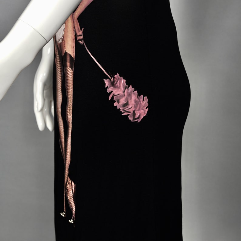 May include: Black dress featuring a pink floral design and a brown, snake-like pattern. The dress is displayed on a mannequin, showcasing its form and design. The dress has a unique, artistic aesthetic.