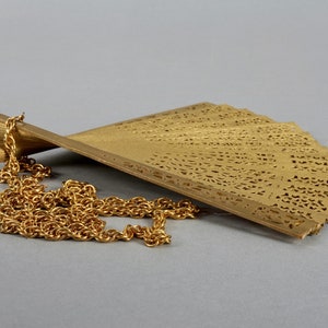 May include: A gold-colored metal fan pendant with a delicate, intricate design. The fan is attached to a gold chain.