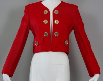 May include: A red cropped blazer with gold buttons. The blazer has a v-neck and long sleeves.