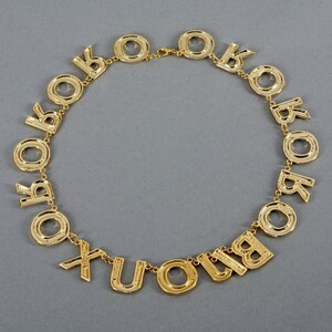 May include: A gold-tone necklace with letter charms spelling out "XOXO" and "YOU" in a circular design.