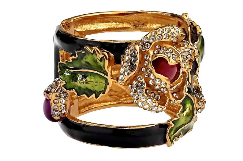 Puede incluir: Un brazalete de oro con base de esmalte negro y un gran dise&ntilde;o de rosa engastada. La rosa est&aacute; adornada con brillantes transparentes y una piedra central roja. El brazalete tambi&eacute;n presenta hojas de esmalte verde y bayas de esmalte morado.