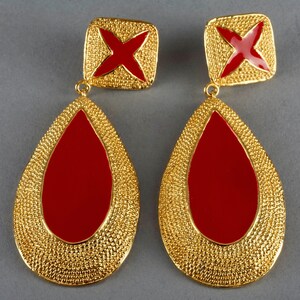 May include: A pair of gold tone earrings with red enamel teardrop shaped drops and a square top with a red enamel cross.