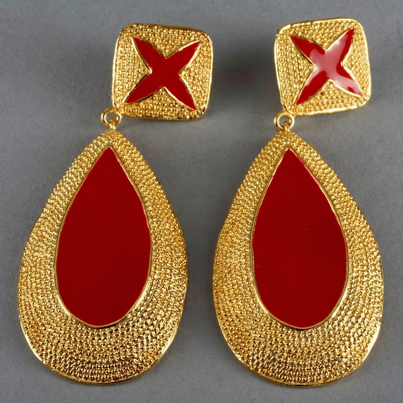 May include: A pair of gold tone earrings with red enamel teardrop shaped drops and a square top with a red enamel cross.