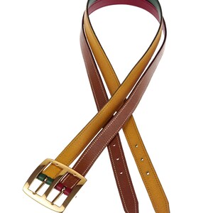 Pode incluir: Um cinto de couro revers&iacute;vel com uma fivela dourada. O cinto &eacute; marrom e amarelo de um lado e verde, vermelho e marrom do outro.