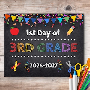 May include: A black chalkboard sign with colorful confetti and bunting at the top. It features the text 1st Day of 3RD GRADE and 2026-2027 in white and multi-colored chalk-style font, decorated with a red apple, a pencil, a crayon, and scissors.