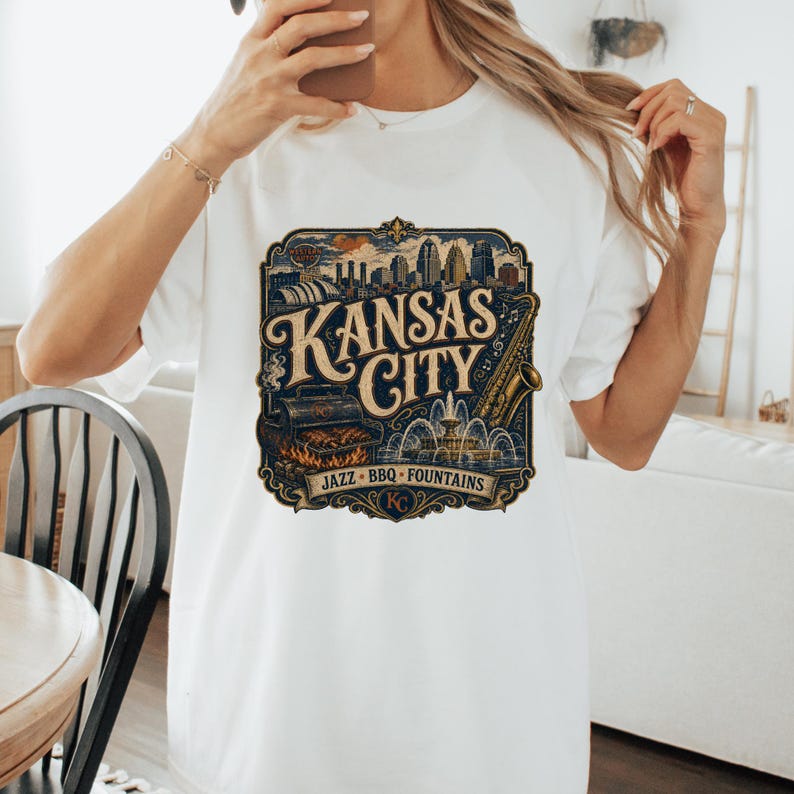 K&ouml;nnte beinhalten: Wei&szlig;es T-Shirt mit einem Grafikdesign im Vintage-Stil von Kansas City. Das Design umfasst die Skyline der Stadt, ein Saxophon, einen Grill und die Worte "Kansas City, Jazz, BBQ, Fountains".