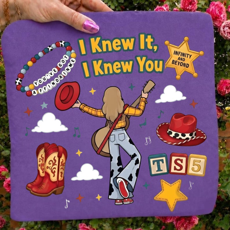 May include: A purple square pillow featuring a cartoon illustration of a person with a guitar, a red hat, cowboy boots, a beaded bracelet with the text YOU'VE GOT A FRIEND IN ME, a sheriff badge with INFINITY AND BEYOND, and the text I KNEW IT, I KNEW YOU.
