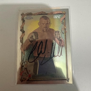 Puede incluir: Una tarjeta coleccionable Topps Chrome UFC 2024 con un luchador en posición de combate. La tarjeta tiene un acabado metálico brillante con la firma del luchador. La tarjeta está dentro de una funda protectora.