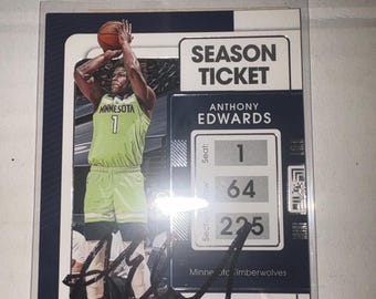 May include: A Panini Contenders basketball trading card featuring Anthony Edwards of the Minnesota Timberwolves. The card displays a Season Ticket design with the player in a lime green jersey, a black autograph, and seat, row, and section numbers.