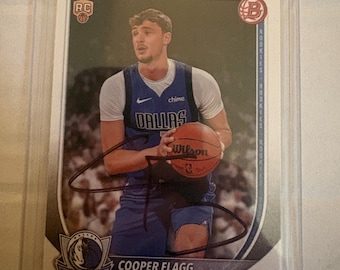Può includere: Una carta collezionabile da basket Bowman che ritrae Cooper Flagg con una maglia blu dei Dallas Mavericks mentre tiene in mano un pallone Wilson. La carta include un autografo a inchiostro nero, un logo rookie RC, il logo dei Mavericks e il testo Cooper Flagg.